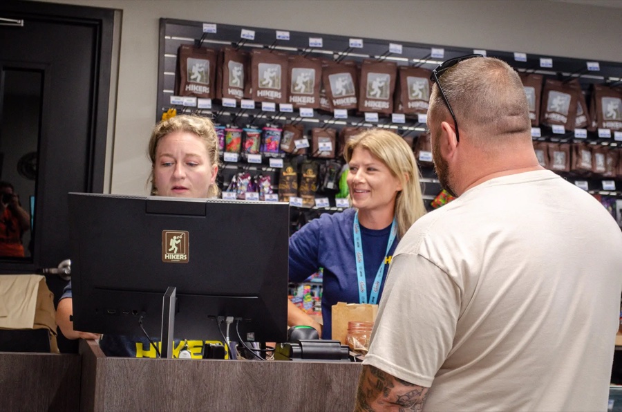 Two budtenders helping a customer at the counter